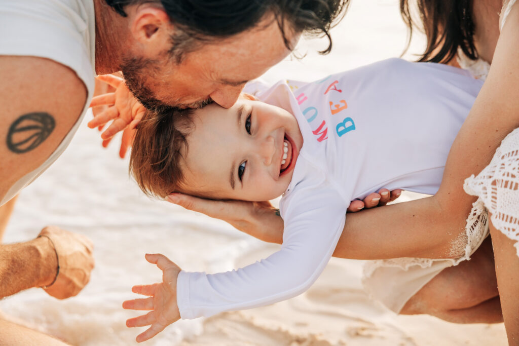Parents and toddler laughing together on a Cayman beach